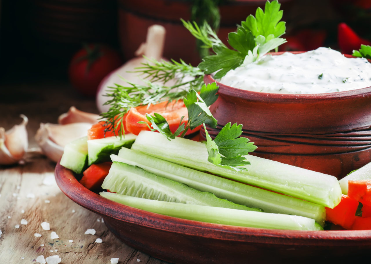 Healthy snacks: cucumber sticks, celery and carrots with ranch dressing, vintage wooden background, selective focus