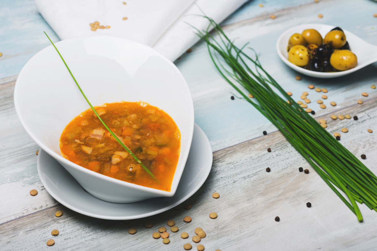 lentil soup with chorizo and vegetables on a decorated wooden table
